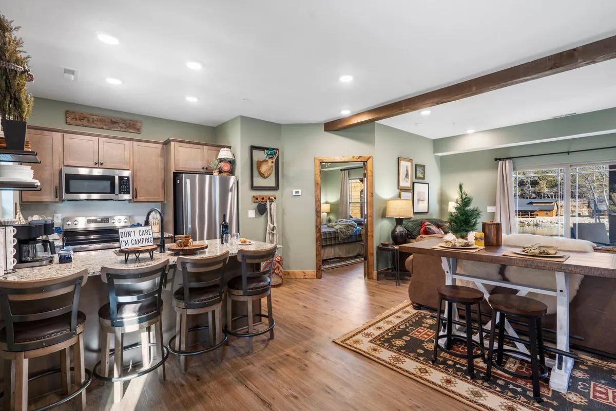 A spacious kitchen with an island featuring bar stools, decorative wall art, and a full suite of appliances. The room is arranged for both food preparation and social interaction, emphasizing communal and festive experiences.